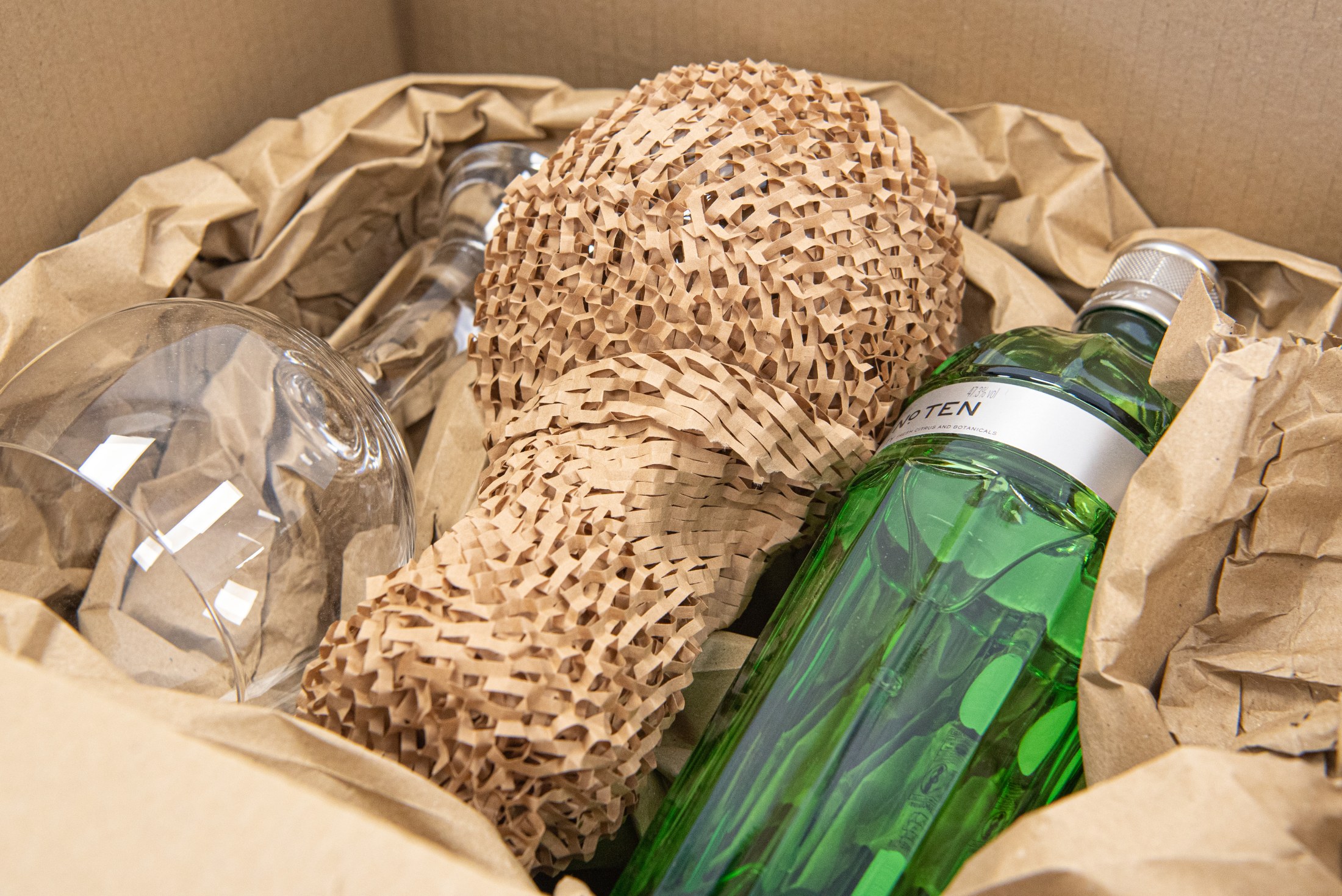 Glassware and bottles protected with expanded paper and paper cushioning inside a carton