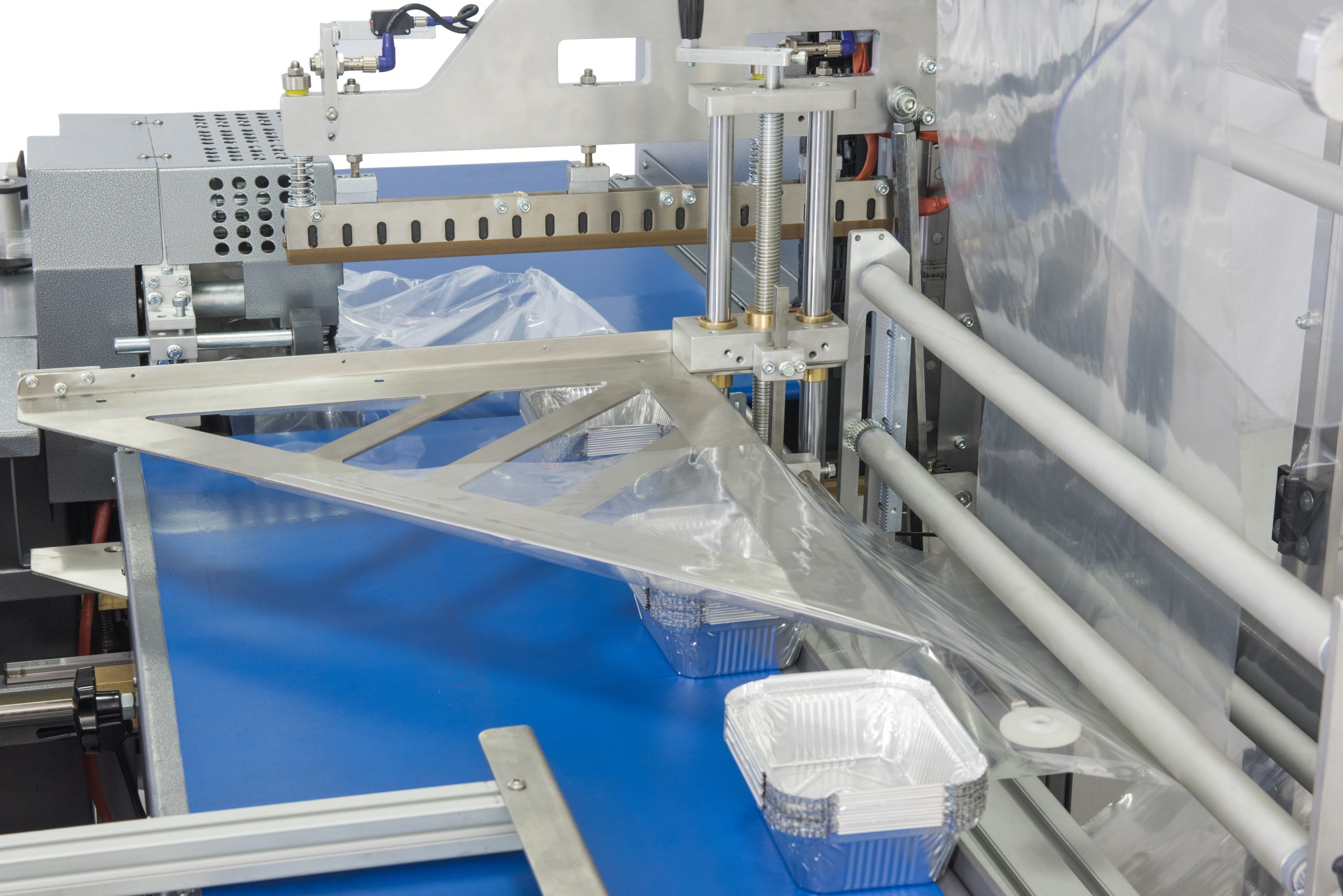 Shrink-wrapping equipment feeding clear film around products on a conveyor